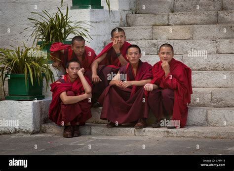 Young Buddhist Monks Sit On The Steps Just Outside The Courtyard At The