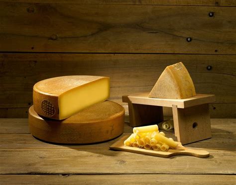 A Cheese Grater And Slice Of Cheese On A Wooden Table Next To A Block