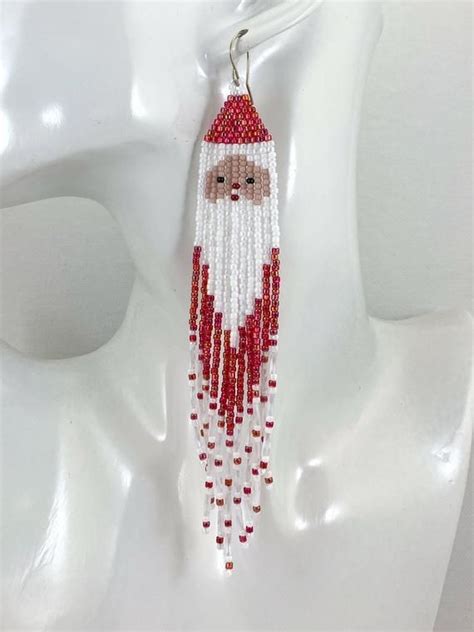 A White Mannequin Head Wearing Red And White Beaded Santa Claus Earring