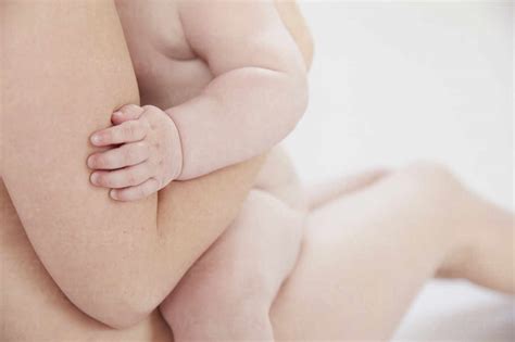 Naked Mother Comforting Naked Baby Resting On Lap Stock Photo