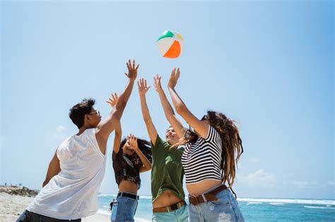 Grupo de jovens alegres brincando bola de vôlei Foto Premium