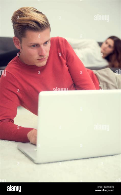 Handsome Blond Man Lying On Carpet And Looking At Laptop And Woman