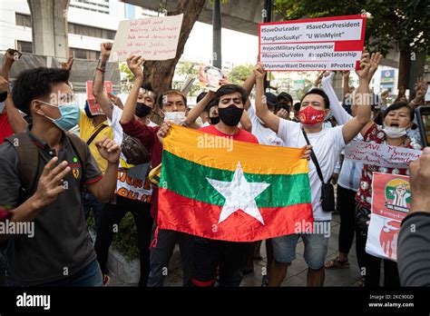 Myanmar residents in Bangkok hold up a Myanmar national flag while ...