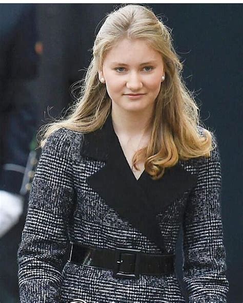 A Woman In A Black And White Coat Is Walking With Her Hand On Her Hip