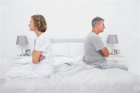 Couple Sitting On Different Sides Of Bed Not Talking After Dispute