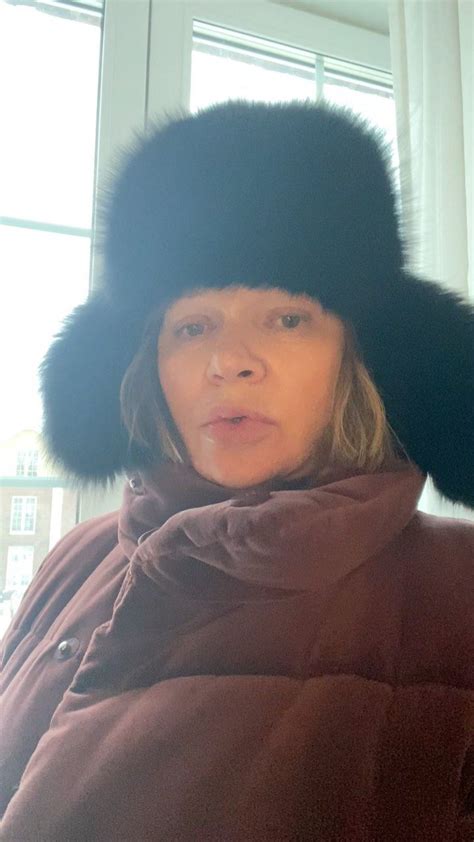 A Woman Wearing A Fur Hat In Front Of A Window