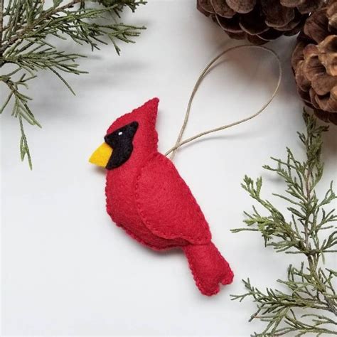 A Red Bird Ornament Hanging From A Pine Branch