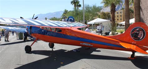 An Orange And Blue Plane Is Parked On The Street With People Around It