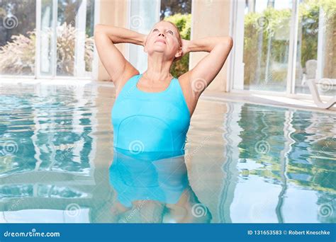 Old Woman In Pool Doing Stretching Exercise In Aqua Gym Class Stock