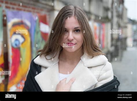 Belle jeune fille blonde modèle regardant la caméra Elle porte un manteau chaud blanc et noir