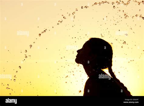 Indian Girl Splashing Water Over Herself At Sunset Silhouette India