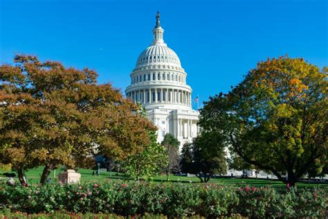 United States Capitol Building With Colorful Trees And A Green Lawn