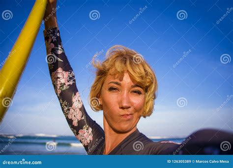 Young Attractive And Happy Blonde Surfer Woman In Swimsuit Holding Surf