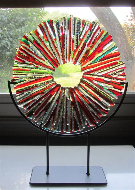 A Glass Plate With Many Different Colored Sticks In It On A Stand Next To A Window