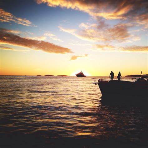 Two People Standing On The Back Of A Boat In The Middle Of The Ocean At