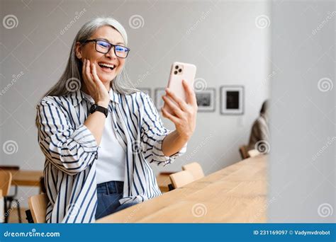 Cheerful White Haired Mature Woman Laughing And Using Cellphone Stock