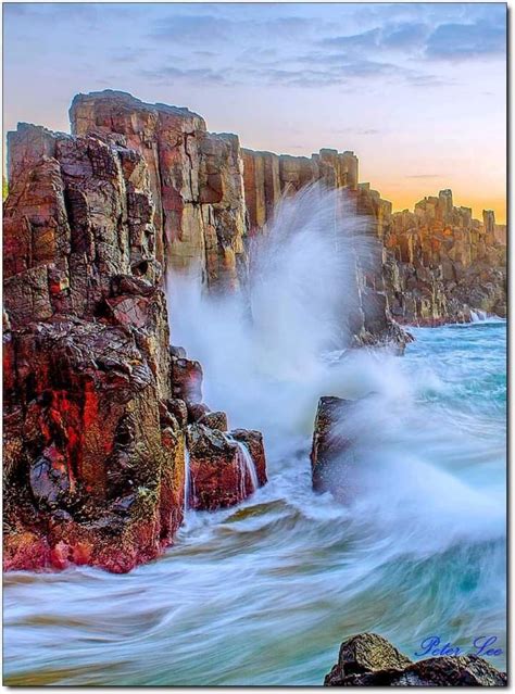 waves crashing against the rocks at sunset