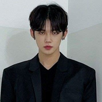 A Man With Black Hair Wearing A Black Suit And Dark Shirt Standing In