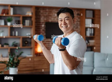 Cheerful Korean Mature Man Doing Strength Exercises For Arms Lifting