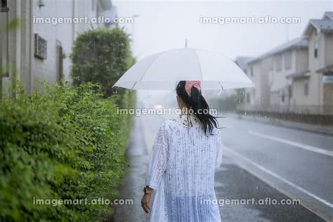 雨の中を傘をさして歩く女性の写真素材 197624875 イメージマート