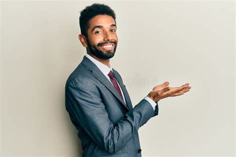 Handsome Hispanic Man With Beard Wearing Business Suit And Tie Pointing