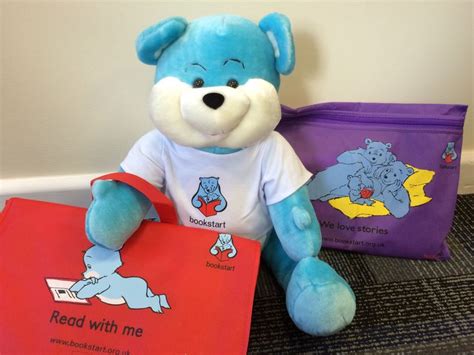 A Blue Teddy Bear Sitting Next To Two Bags