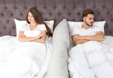 Upset Young Couple With Relationship Problems Lying Separately In Bed