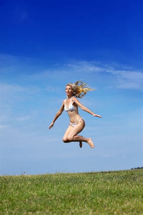 La Donna Felice In Bikini Bianco Salta In Un Campo Di Verde Dell Estate
