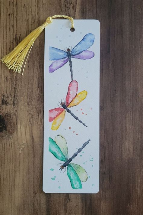 A Watercolor Bookmark With Dragonflies Painted On It