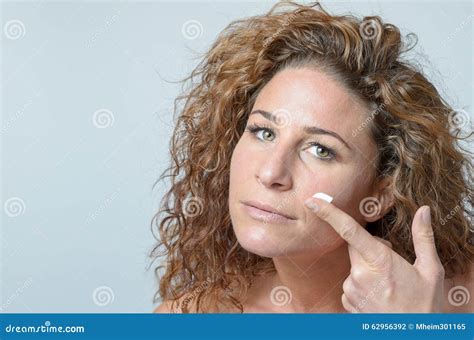 Mujer Que Aplica La Crema Hidratante A Su Piel Foto De Archivo Imagen