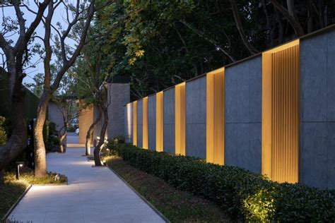 A Long Walkway Between Two Buildings With Trees And Bushes On Both