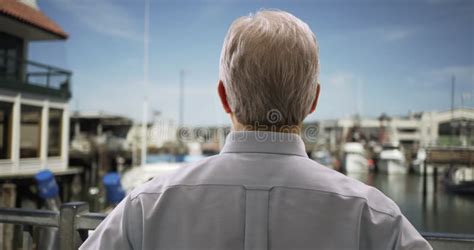 Portrait Of Mature White Man Standing On Seaport Looking At Sailboats