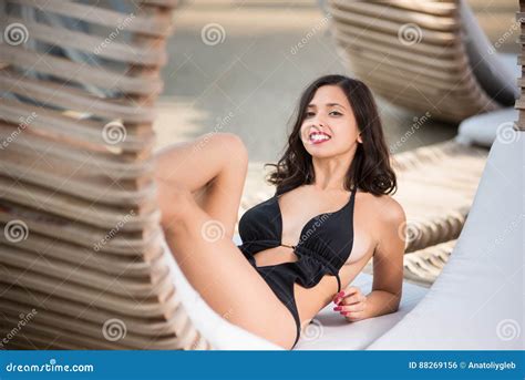 Close Up Of Brunette Female In A Black Swimsuit Lying Propped On Her