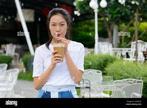 Young Beautiful Asian Woman Drinking Coffee At The Coffee Shop Outdoors