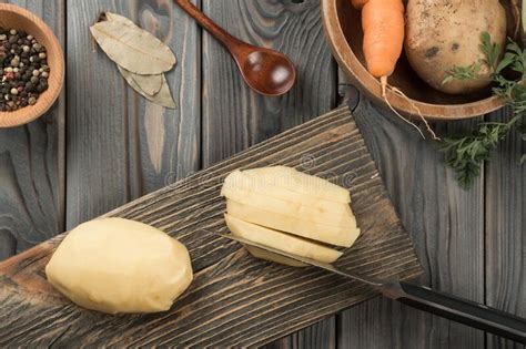 Cutting Into Slices Raw Yellow Potato With Knife On Kitchen Wooden