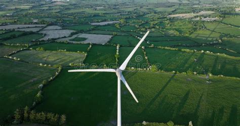 Large Wind Turbine With Blades On Green Field Aerial View Of Green