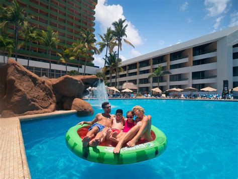 Hombre y mujer con dos niños flotando en sandía inflable en la piscina