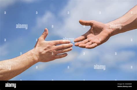 Two Male Hands Reaching Towards Each Other On Isolated Sky Background