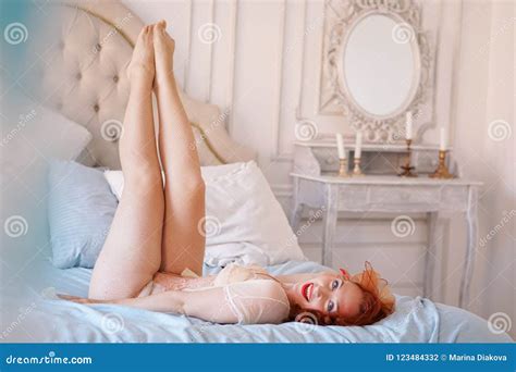 A Luxurious Pin Up Lady Dressed In A Beige Vintage Lingerie Posing In Her Bedroom Alone Stock