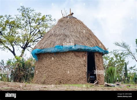 A Traditional Round Mud Hut With Grass Roof And Clay Wall In A Remote