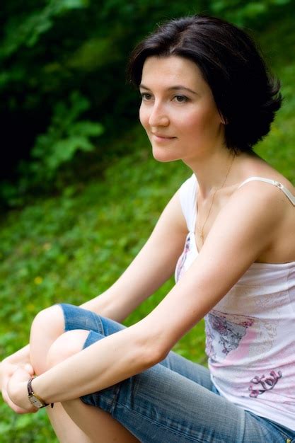 Premium Photo Portrait Of A Smiling Young Woman Sitting Outdoors