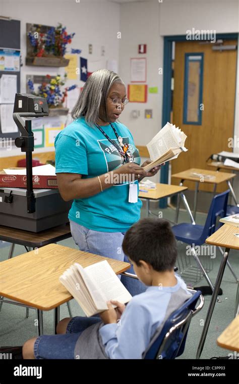 African-American female teacher speaks to students in a middle school Texas classroom Stock ...