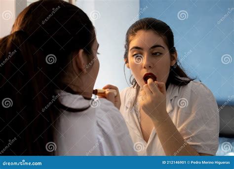 Woman Putting Lipstick On Her Lips In A Room Doing Make Up Stock Image