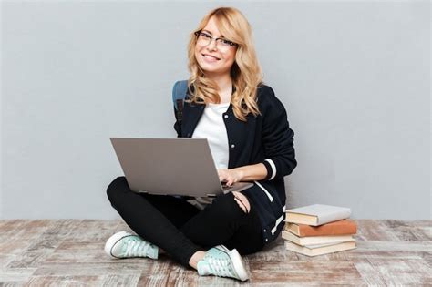 Estudiante de mujer joven sonriente que usa la computadora portátil