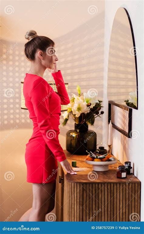 A Beautiful Girl In A Red Dress Looks At Herself In The Mirror Stock Image Image Of Brunette