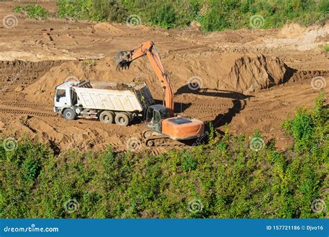 Excavator Loading Dumper Truck With Sand At Construction Site Stock