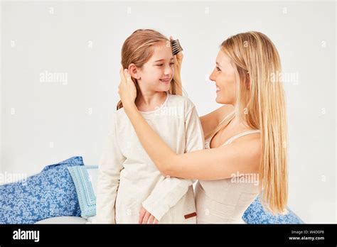 Caring Mother Combs Her Daughters Blond Hair In The Bedroom Stock