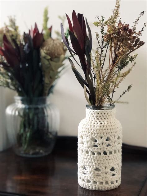 Two Crocheted Vases With Flowers In Them Sitting On A Table Next To Each Other