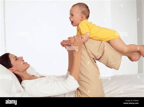 Female Brunette Hair Wearing White Vest Top Lying On Her Back On A Bed Her Legs Raised And A
