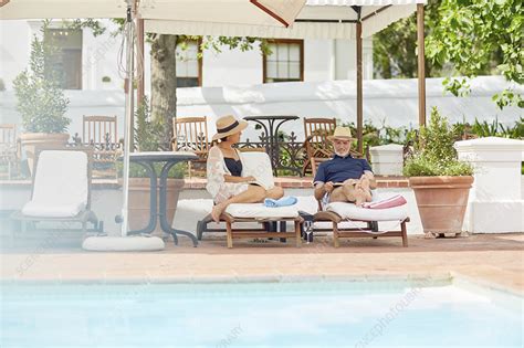 Mature Couple Relaxing At Resort Poolside Stock Image F024 9278